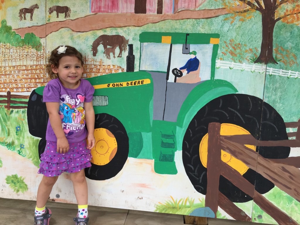 Madiana standing by a farm tractor painting.