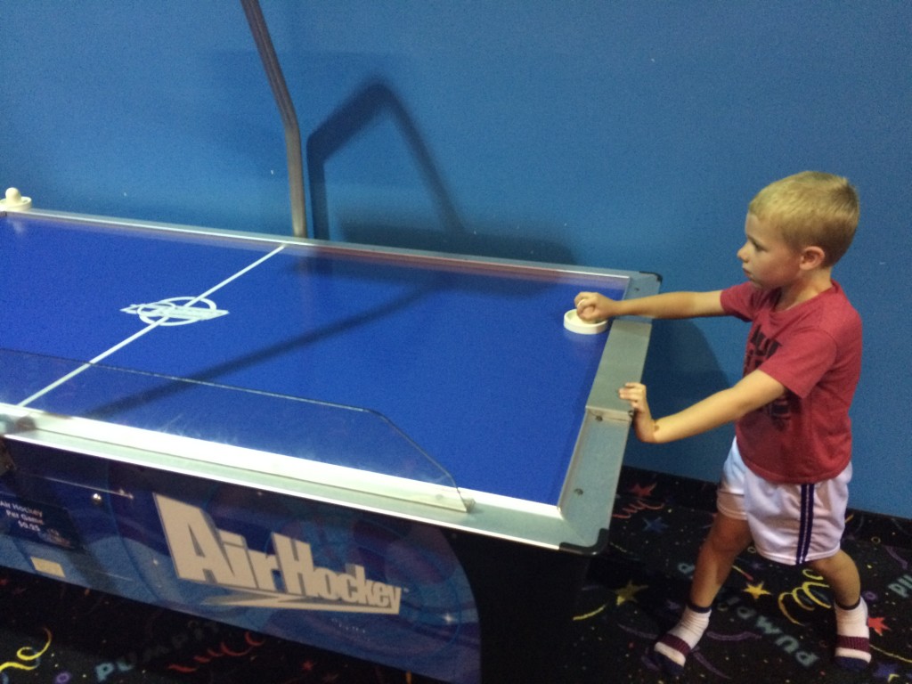 Brecken playing some air hockey with other kids.