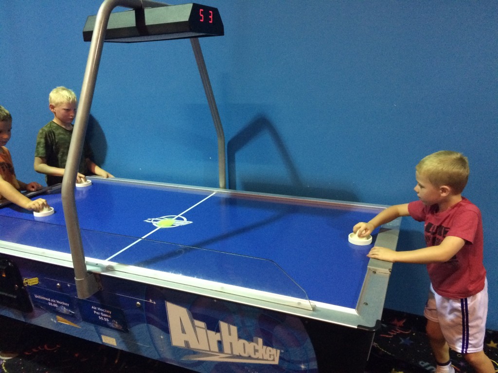 Brecken playing some air hockey with other kids.